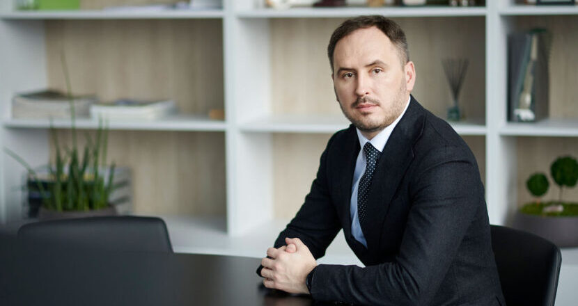 Lietuvos centrinės kredito unijos administracijos vadovas ir valdybos pirmininkas biuro aplinko sėdi prie stalo ir žvelgia į kamerą.
